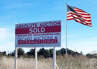 absolute auction sold sign from DeCaro Auctions International and an American flag